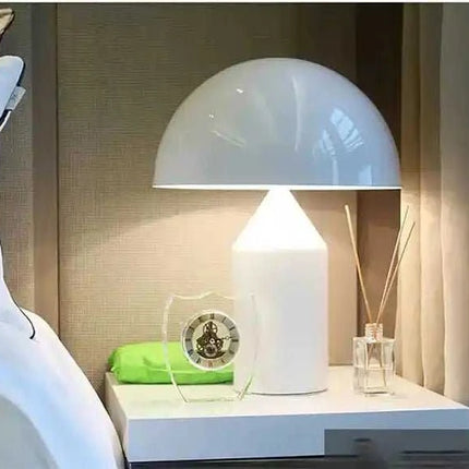Modern White Table Lamp with a dome shade, placed on a bedside table next to a green item.